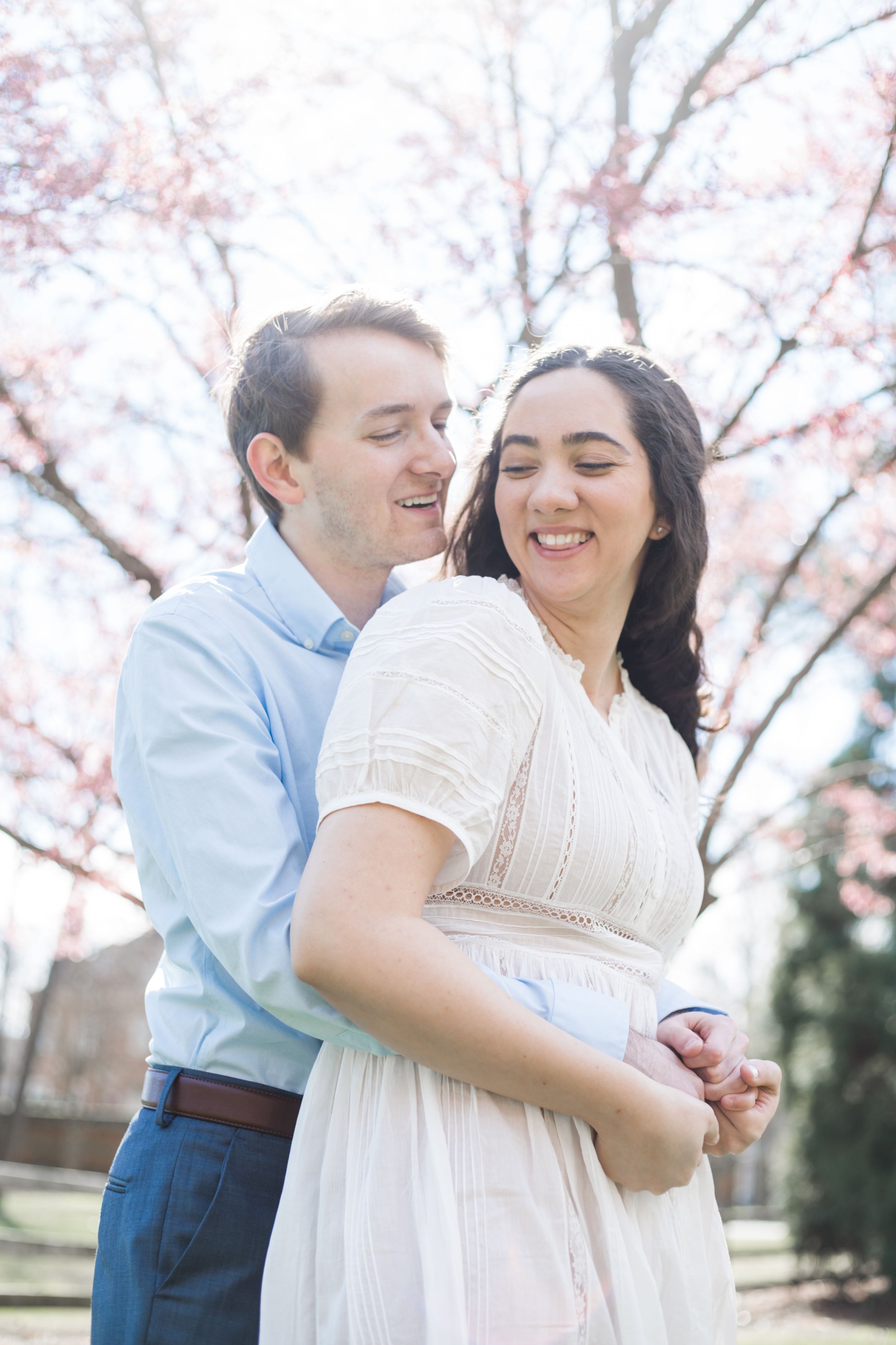 Couple embraces under blooming cherry blossoms in a romantic spring photoshoot.