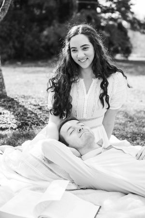 Black and white photos of couple laying on blanket during outdoor portrait session.