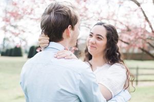 A couple embraces under blooming cherry blossom trees in a romantic spring photo session.