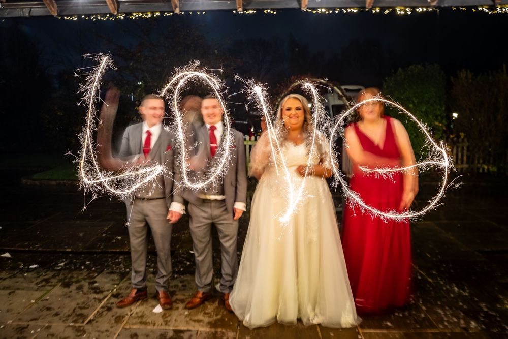 Wedding party writes love with sparklers at night in a joyful outdoor celebration.