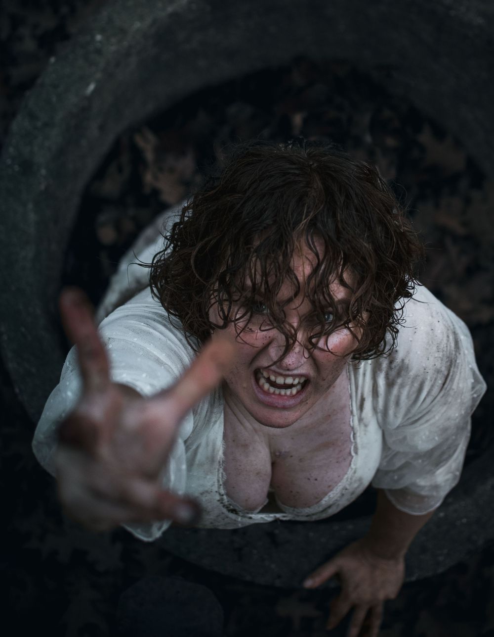 portrait of a person reaching for the photographer from a well