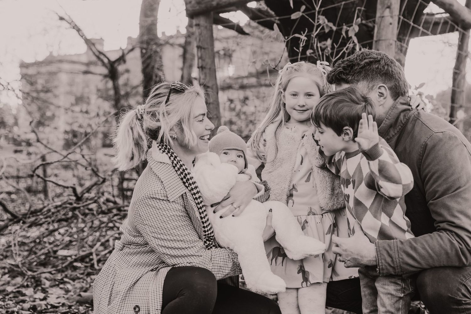 A vintage black and white photograph showing a family gathered together outdoors among trees.