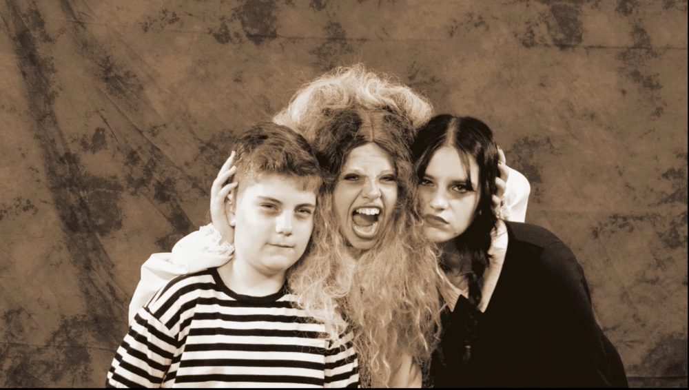 Three performers pose together in a sepia-toned theatrical group photo.