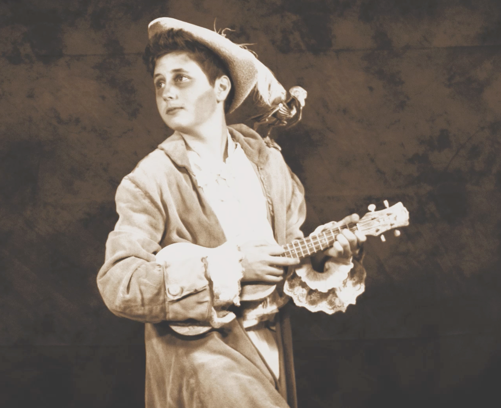 A sepia-toned performer in a cowboy hat strums a ukulele on stage.