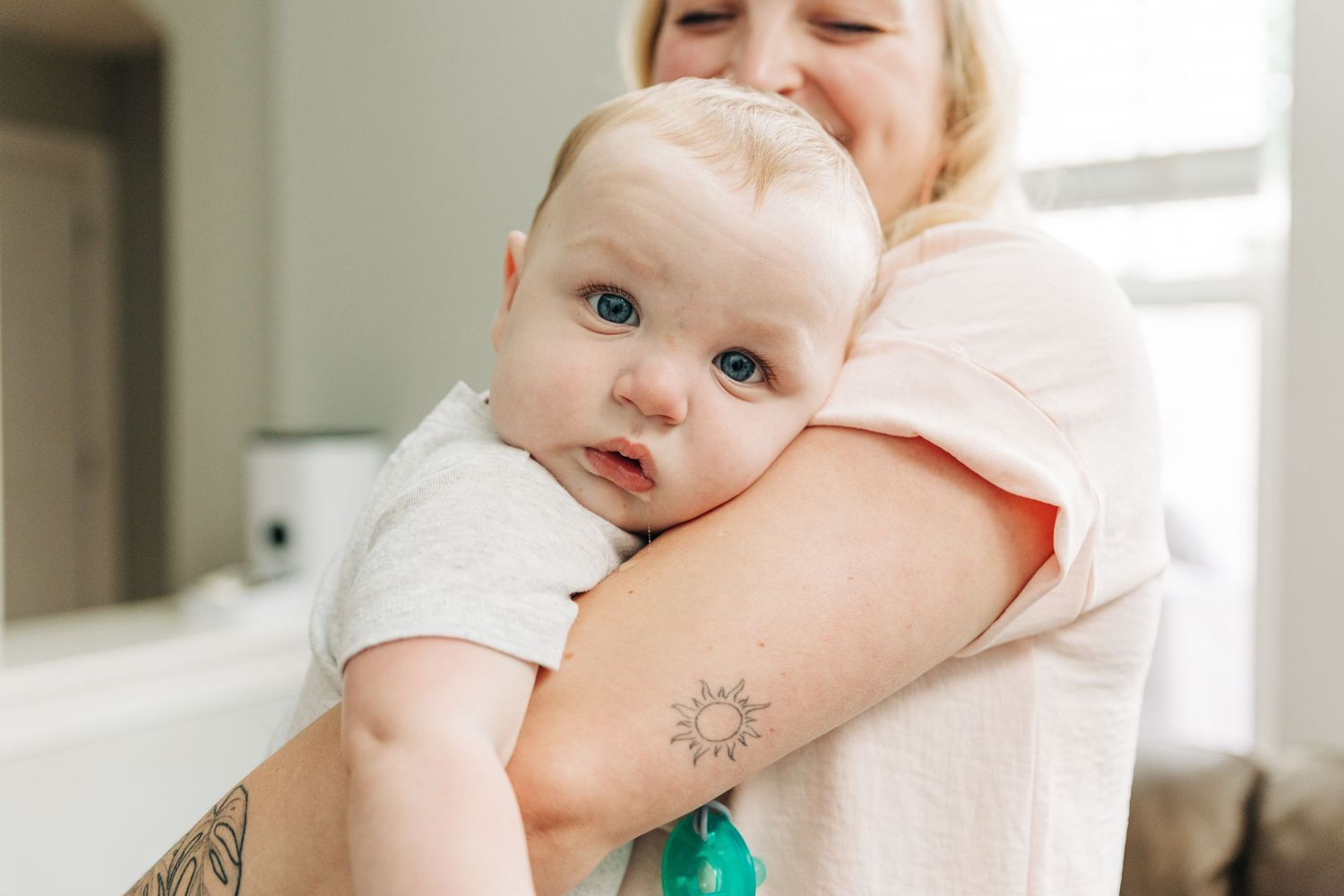 A mother holding her baby who is looking straight into the camera during Charlotte family photos.