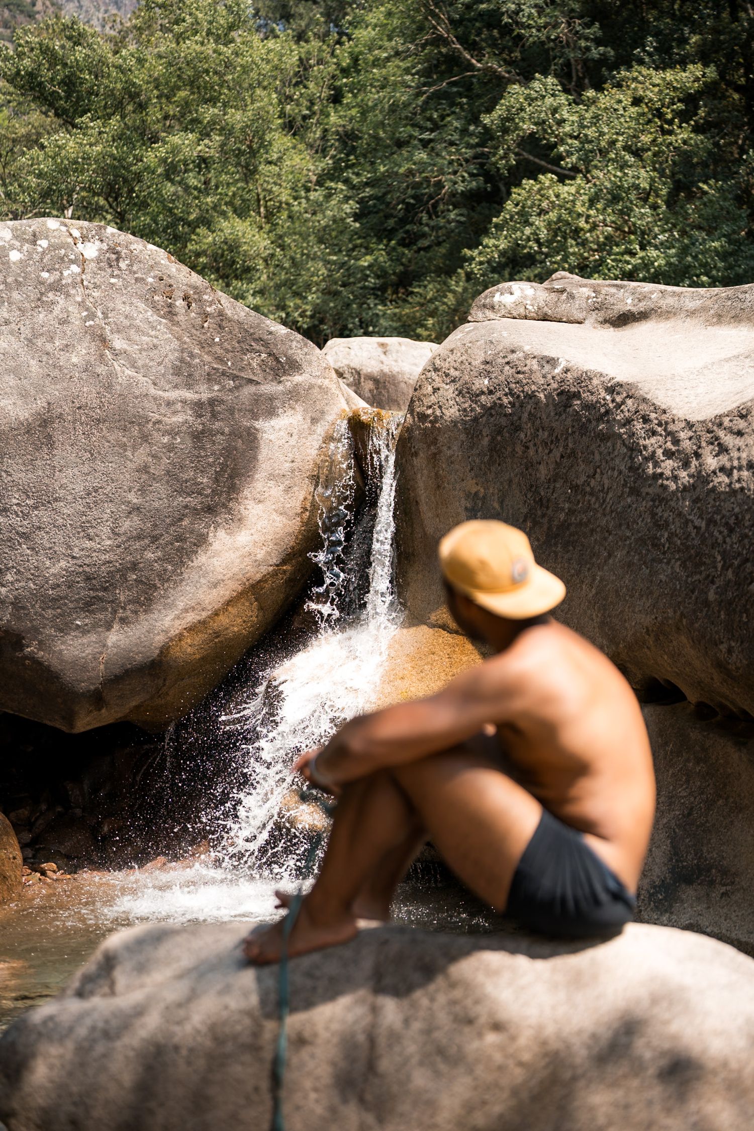 rivière porto en corse avec un baigneur torse nu et une casquette devant une petite cascade