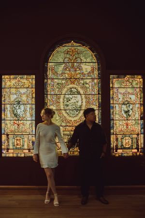 A couple stand against ornate stained glass windows in a Winter Park, Florida museum for their engagement session