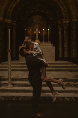 A romantic couple embraces in a dimly lit historic archway with glowing candles creating a moody atmosphere in Florida museum