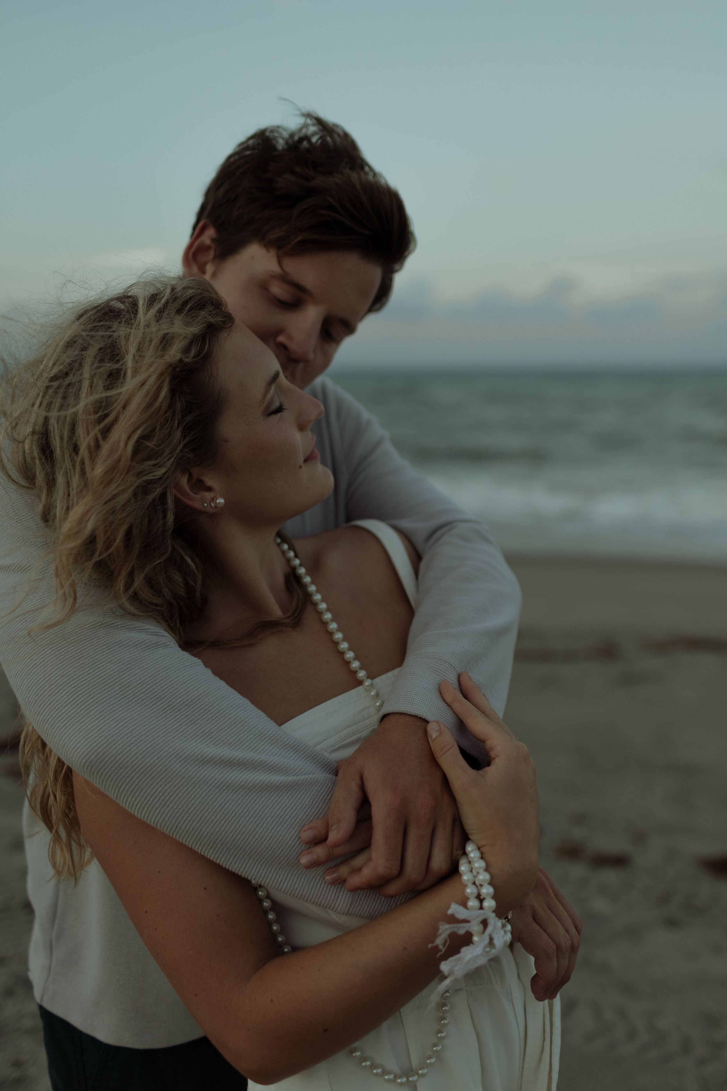 Romantic couple embracing on a moody beach at sunset on Florida beach on the Space Coast.
