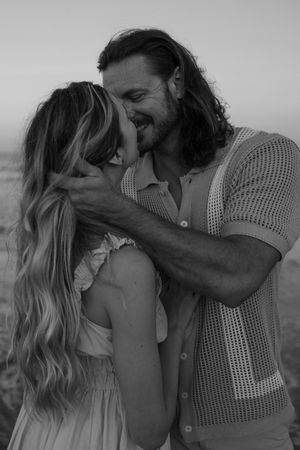 A romantic black and white photo sequence shows a couple embracing and sharing intimate moments on a beach.