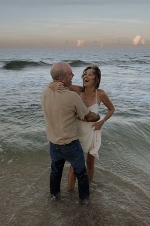 A playful couple shares a romantic moment while standing in the ocean waves at sunset on the Treasure Coast of Florida for anniversary