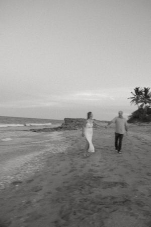 A couple walks along a scenic beach shoreline in black and white, celebrating their anniversary on Treasure Coast at sunset.