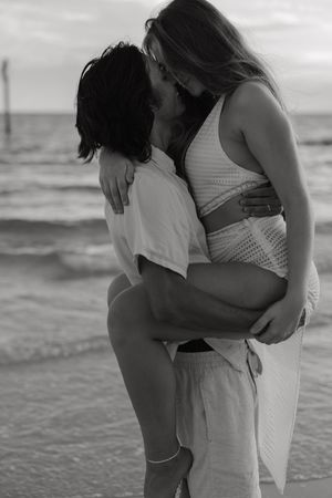 A romantic black and white photo series of a couple embracing on the beach at sunset along Treasure Island, Florida