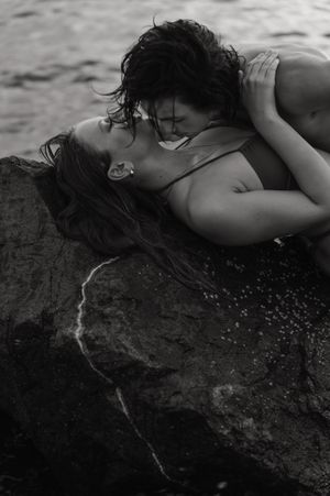 A black and white artistic portrait series shows a person reclining on a textured rock surface.