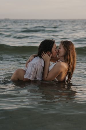A romantic couple embraces while floating in the ocean water during sunset.