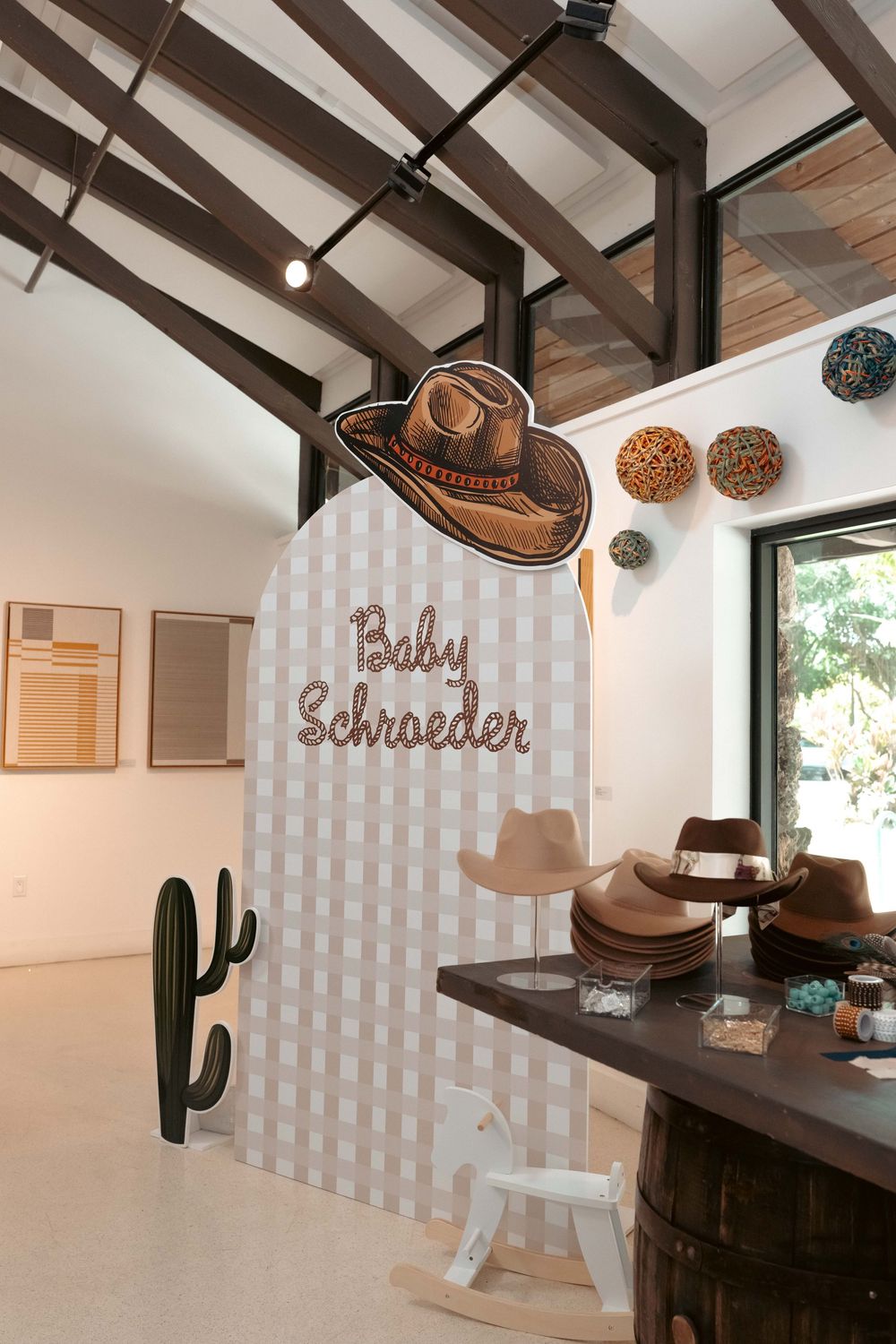 Western-themed baby shower backdrop with Baby Schroeder sign, cowboy hat decor, cactus cutout, and hat bar display.