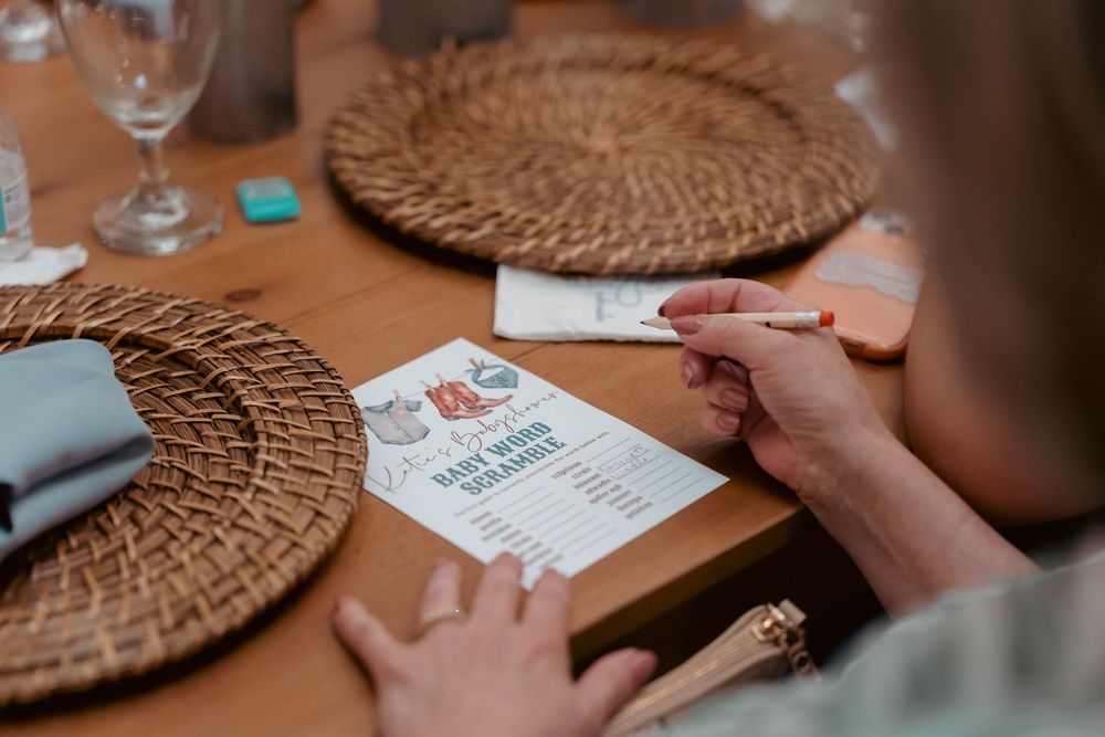 Guest filling out a baby name guessing game card at a baby shower table.