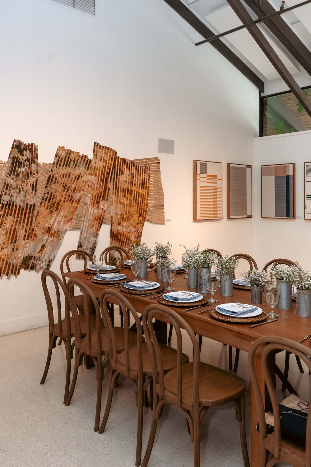 Western baby shower dining area with long wooden table, bentwood chairs, baby's breath centerpieces, and gallery wall.