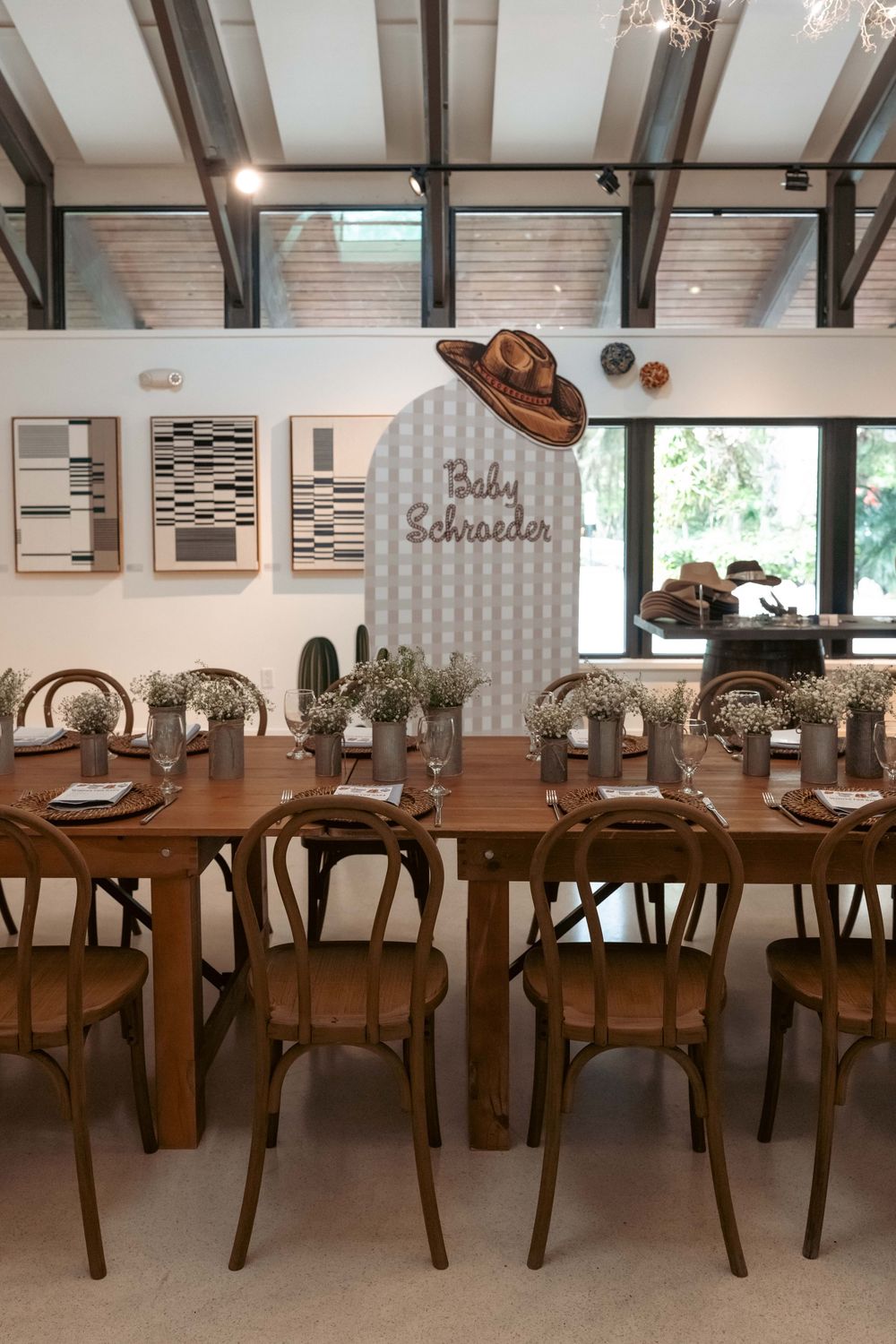 Elegant western baby shower venue with long wooden tables, bentwood chairs, and Baby Schroeder arch backdrop.