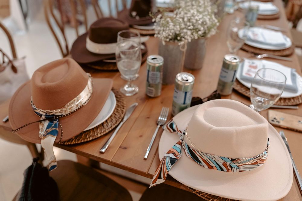 Decorated felt cowboy hats with colorful bands displayed as place settings on a wooden table.