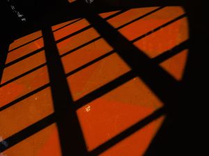 Dramatic shadows cast diagonal lines across an orange-lit floor.