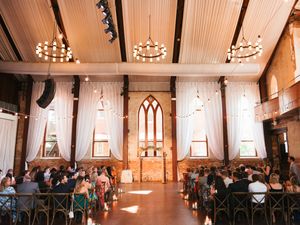 Wedding ceremony in progress inside a church with white walls and gothic windows.