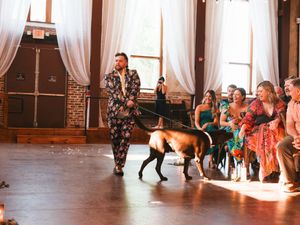 Wedding guests dancing and celebrating in an elegant reception hall with white curtains.