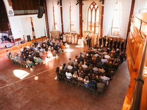 Wedding ceremony in a historic brick church with exposed wooden beams and white drapes.