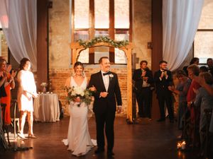 Wedding ceremony in a rustic brick venue with elegant lighting and white drapes.