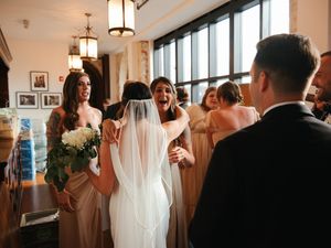 Wedding celebration captured in an elegant venue with natural light streaming through large windows.