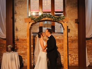 Interior of a rustic brick chapel decorated with white curtains and wooden beams.