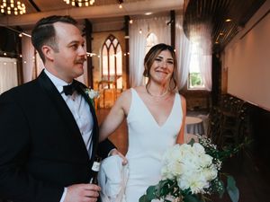 Elegant indoor wedding reception with chandelier lighting and white decor.