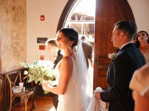 Wedding ceremony entrance at a historic brick church with elegant floral arrangements.