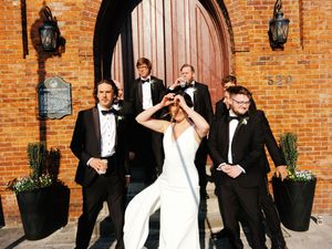 Wedding party gathered outside a brick church entrance with arched doorways.