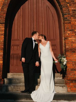 Wedding couple posing in front of rustic brick archways.