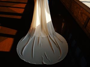 Flowing white wedding dress train photographed in dramatic lighting.