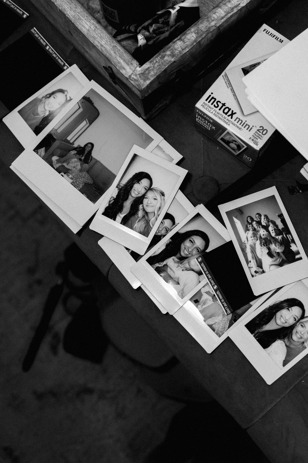 Black and white flat lay of Fujifilm Instax Mini photos scattered on a table.