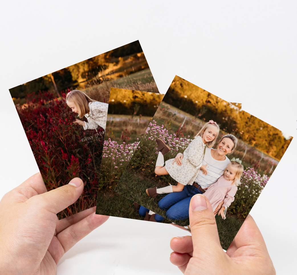 A series of hands holding and arranging printed photographs in a white surface showing a warm autumn outdoor scene.