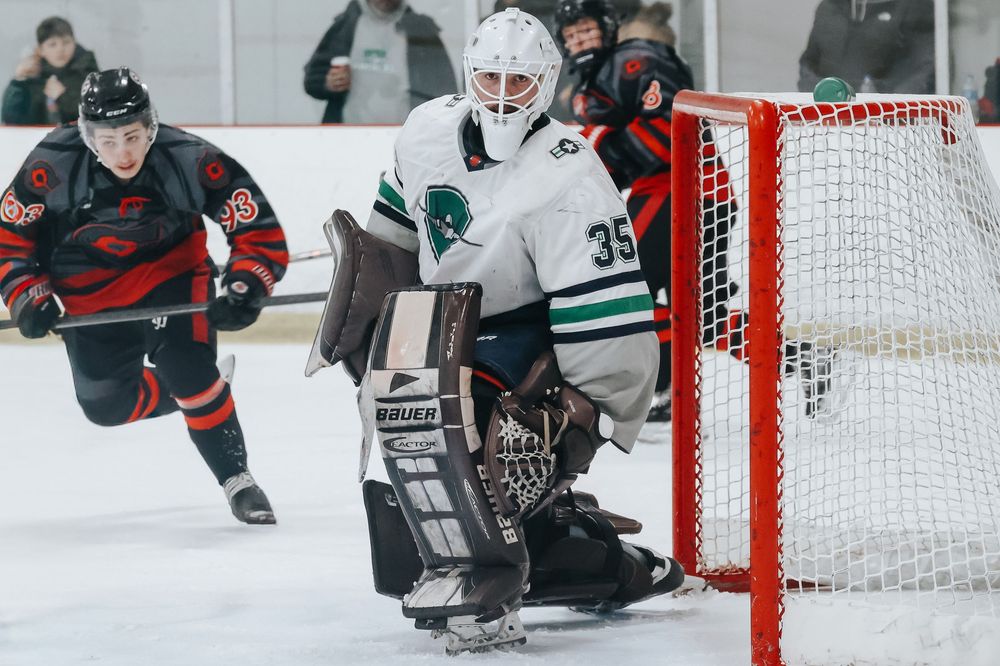 Hockey players battle near the net during an indoor ice hockey game.