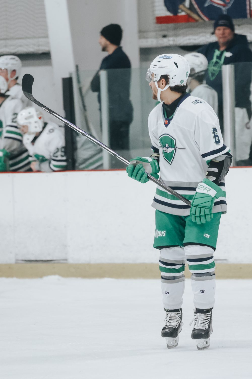 Hockey player in white uniform stands ready on ice during game.