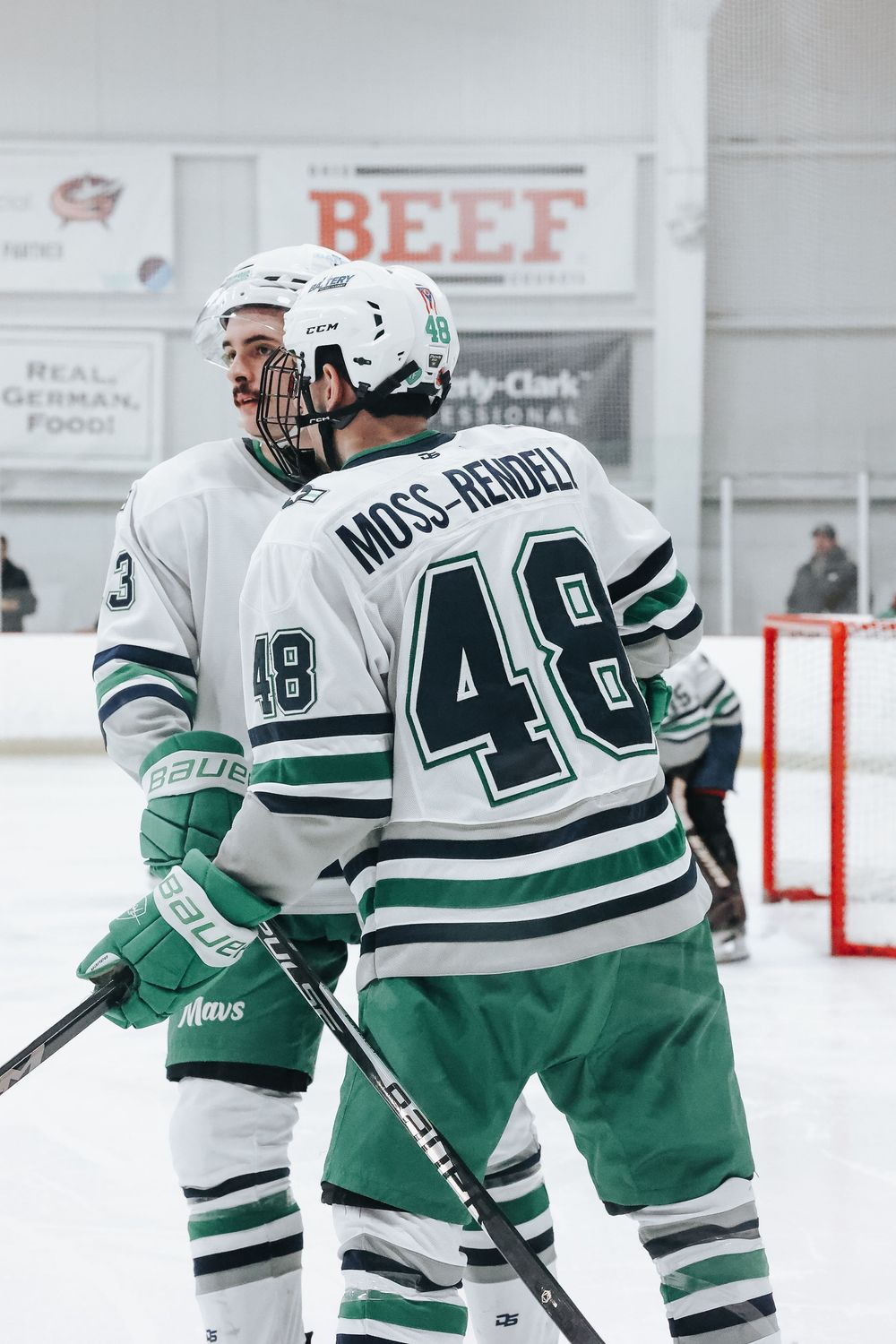 Hockey players in green and white striped jerseys position themselves during gameplay.
