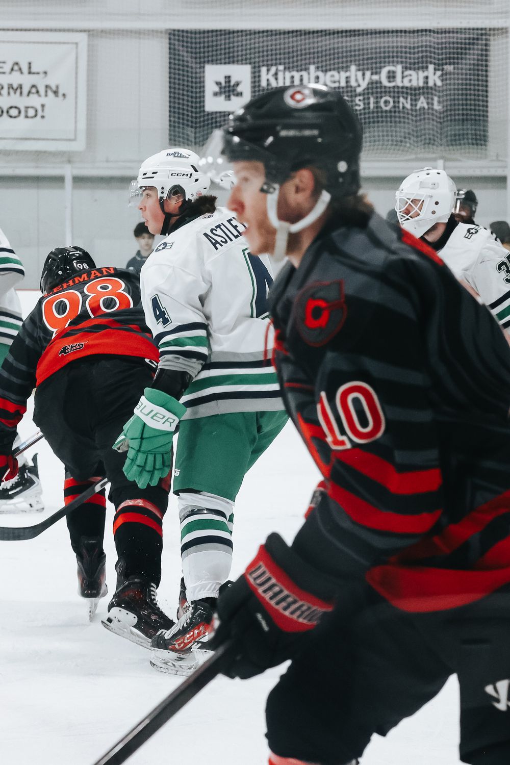 Hockey players battle for possession during intense gameplay on the ice rink.