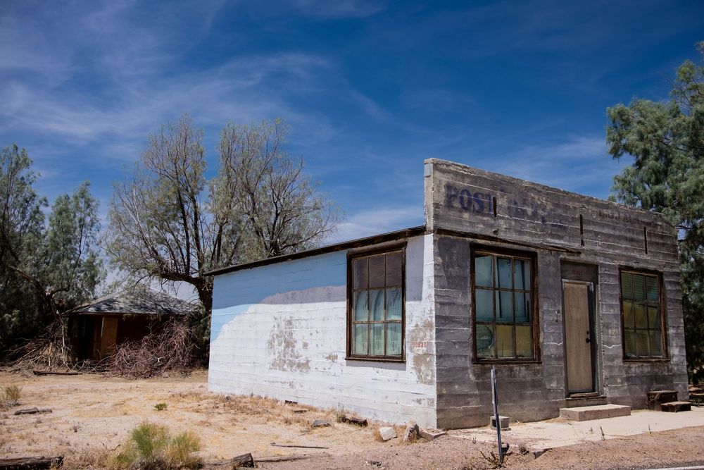A panoramic view of rustic desert cabins with weathered wooden exteriors under a bright blue sky.
