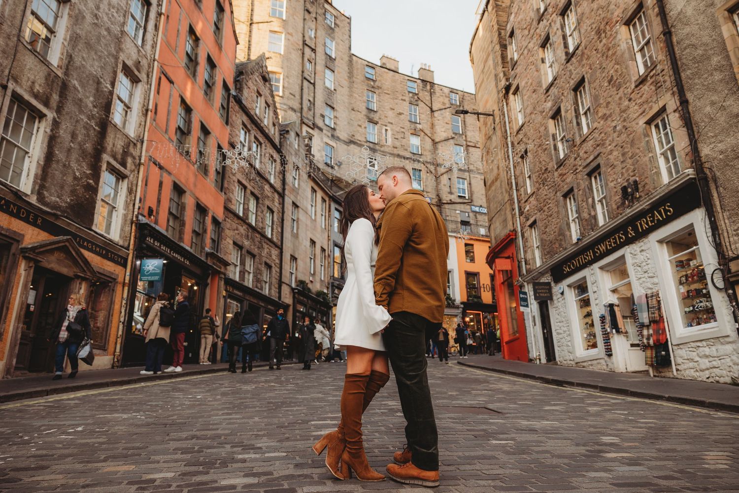 Historic brick buildings line a narrow cobblestone street in Edinburgh's Old Town on a cloudy day.