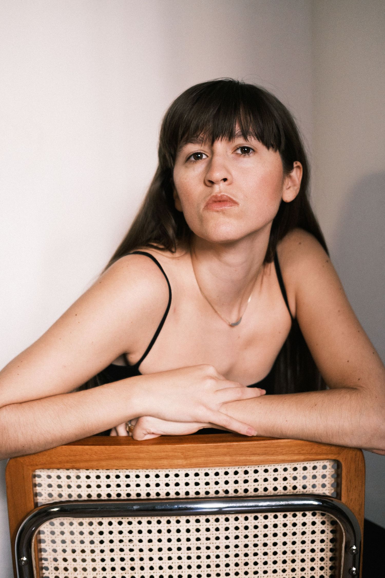A series of artistic portrait shots showing a person resting on a woven cane chair in different poses.
