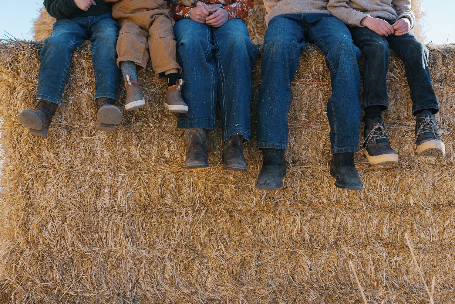 dusty boots of kids on a hay bale commercial ag photographer