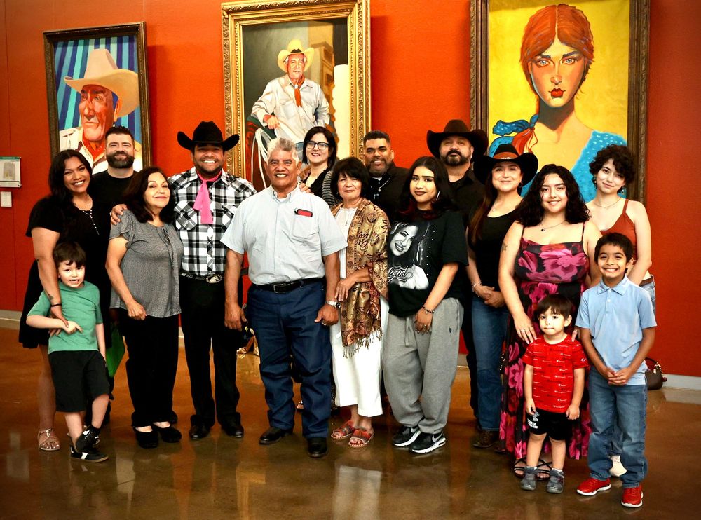 Large family group posing together in an art gallery with colorful paintings on the walls behind them.