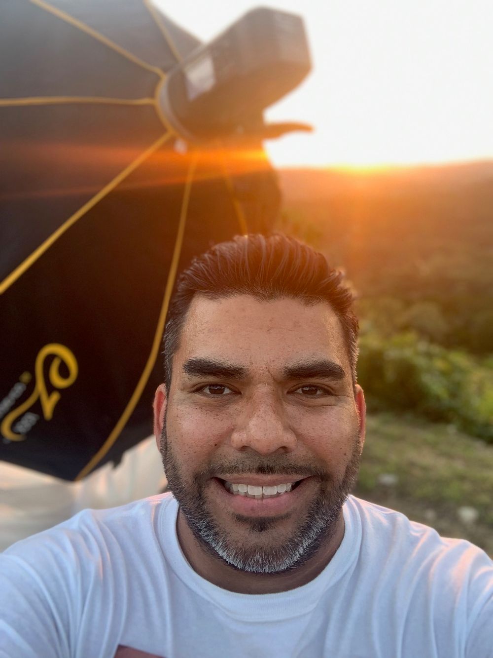 A series of selfie photos taken at sunset showing a person in a white t-shirt with a warm golden glow in the background.