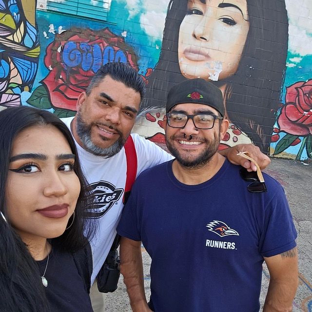 Group of friends posing together in front of colorful graffiti wall in an urban setting.