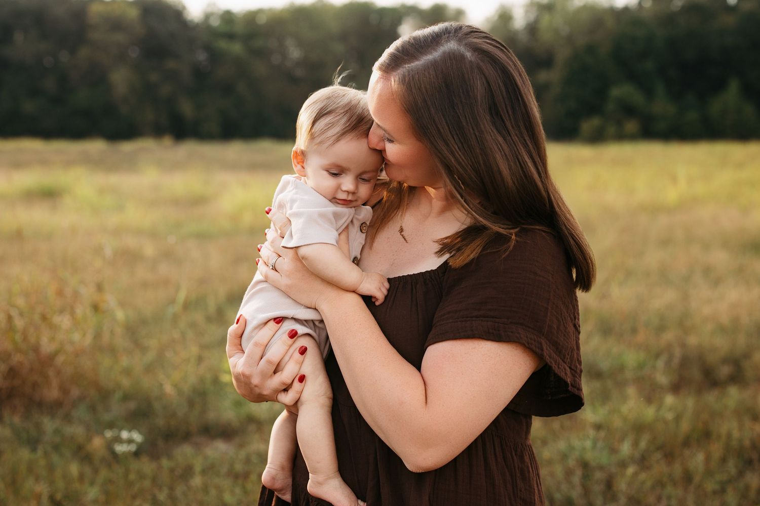 A tender family moment captured in a golden field during sunset as they embrace and share loving moments together.